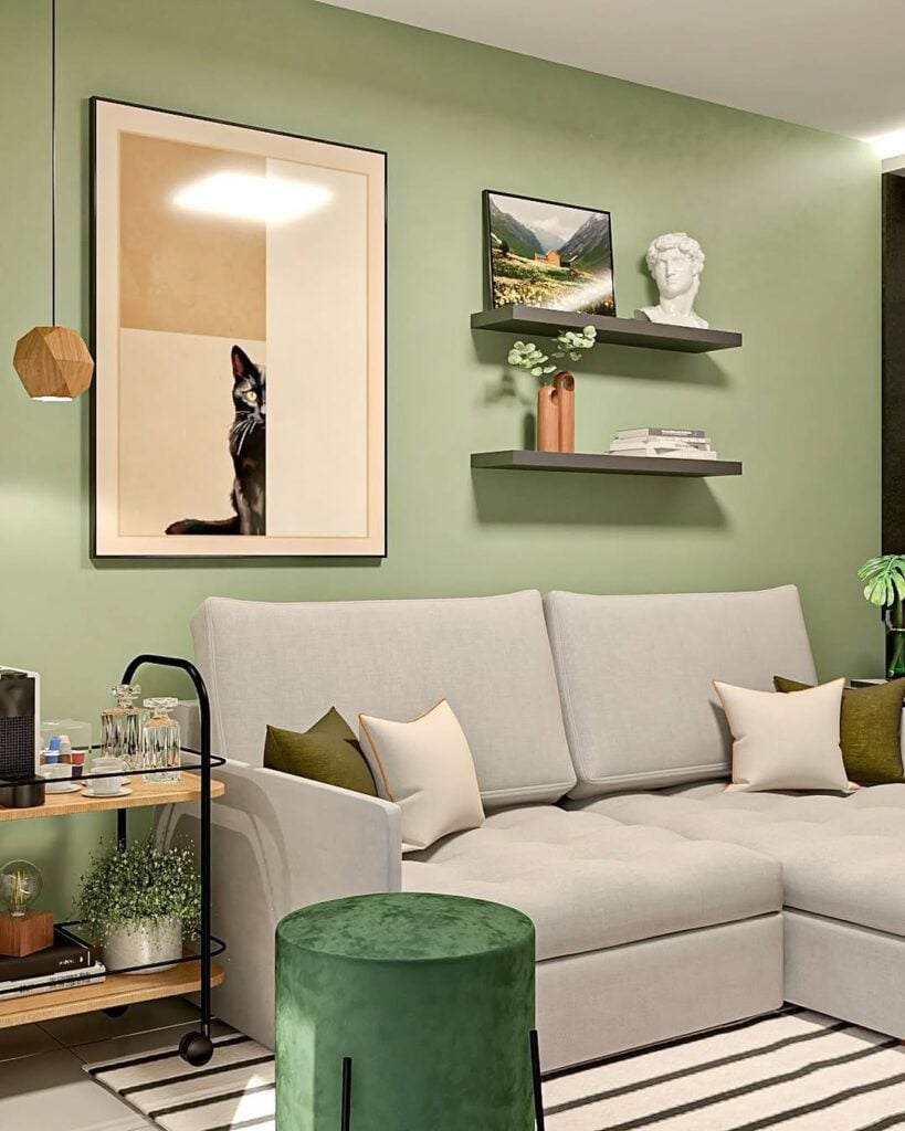Sala de estar com sofá cinza-claro e parede verde com prateleiras e objetos decorativos