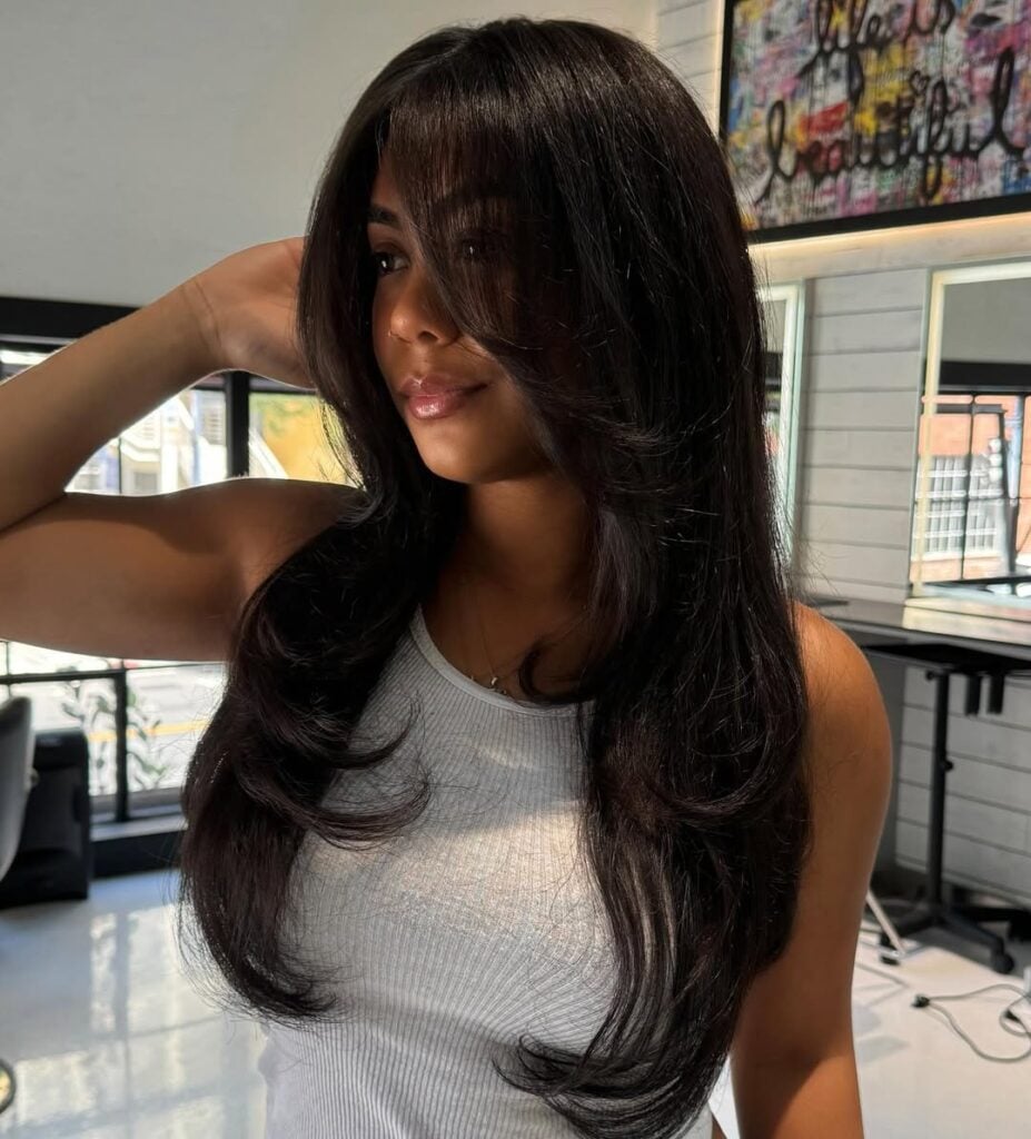 Mulher de pele preta, com blusa branca e cabelo escuro face frame