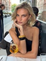 Mulher de pele clara, com look preto e cabelo loiro blunt bob