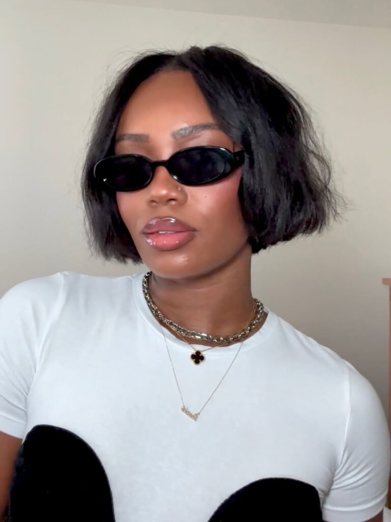 Mulher de pele preta, com roupa branca e cabelo escuro com corte bob