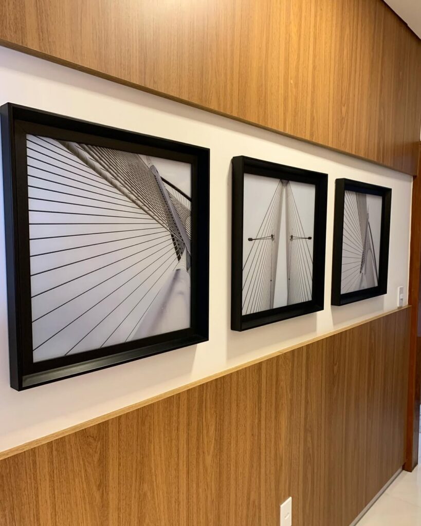 Corredor com painel amadeirado e quadros neutros com bordas pretas