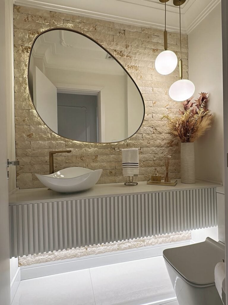 Lavabo em cores neutras com revestimento de tijolinhos, espelho e cuba orgânicos