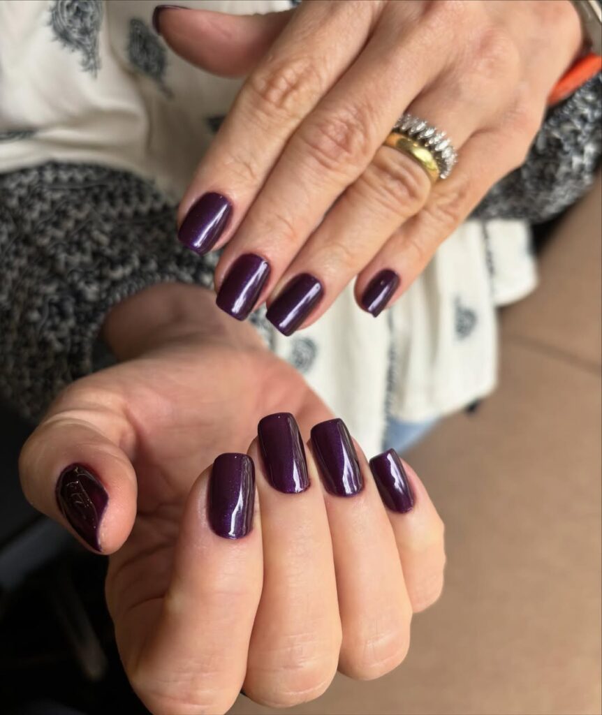 Mãos de pele clara, com anéis e unha quadrada roxo-escuro