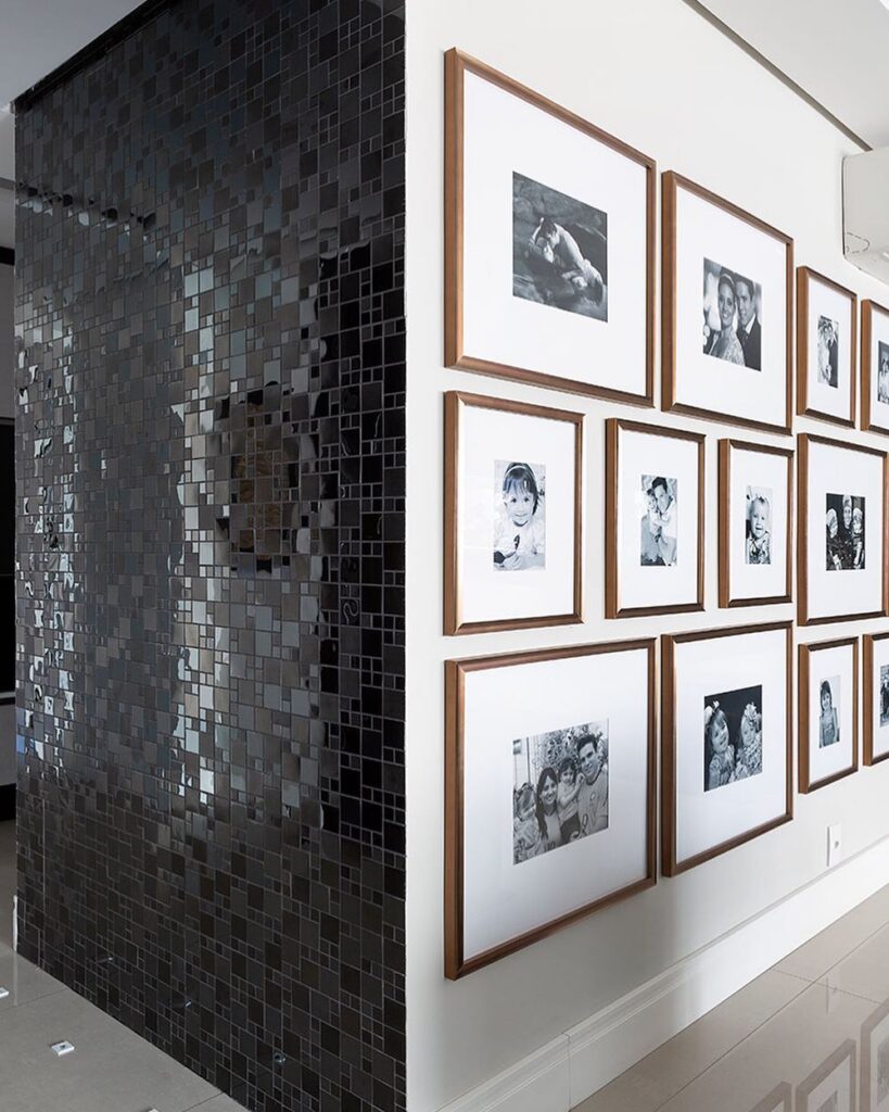 Galeria de quadros em casa, com fundo branco, moldura dourada e fotos em preto e branco