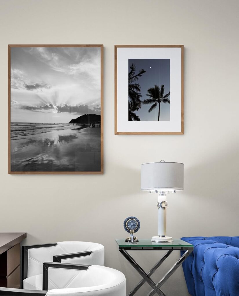 Sala de estar com sofá azul, poltronas brancas e quadros com fotos na parede