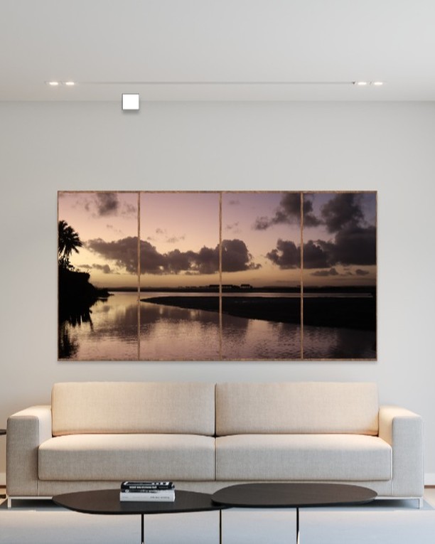 Sala de estar com sofá bege de linhas retas, mesas de centro e fotografia em formato de quadro na parede
