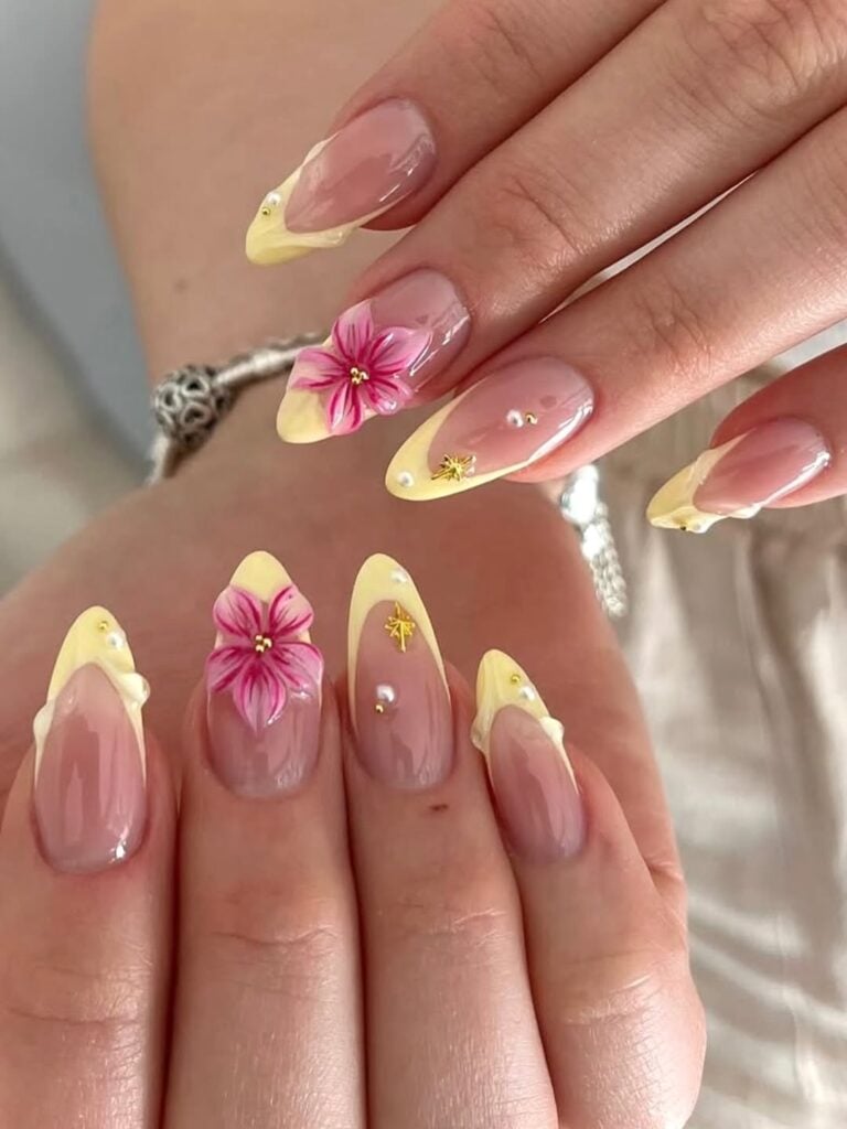 Mãos de pele clara, com unha amendoada com francesinha amarela, flores e pérolas