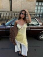 Mulher de pele clara com tênis branco e blusa de renda amarela