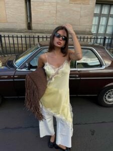 Mulher de pele clara com tênis branco e blusa de renda amarela