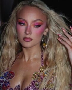 Zara Larsson com cabelo loiro e maquiagem colorida