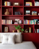 Estante bordô com nichos, prateleiras e livros