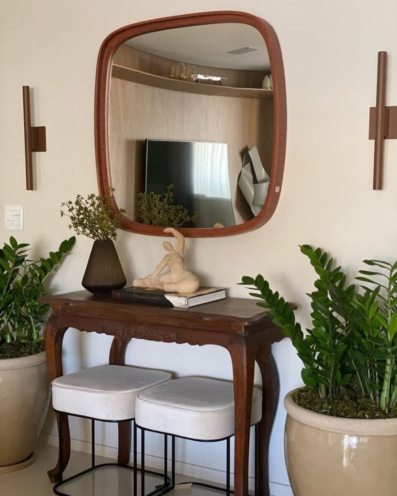 Aparador com pés e detalhes torneados com banquetas modernias e espelho orgânico