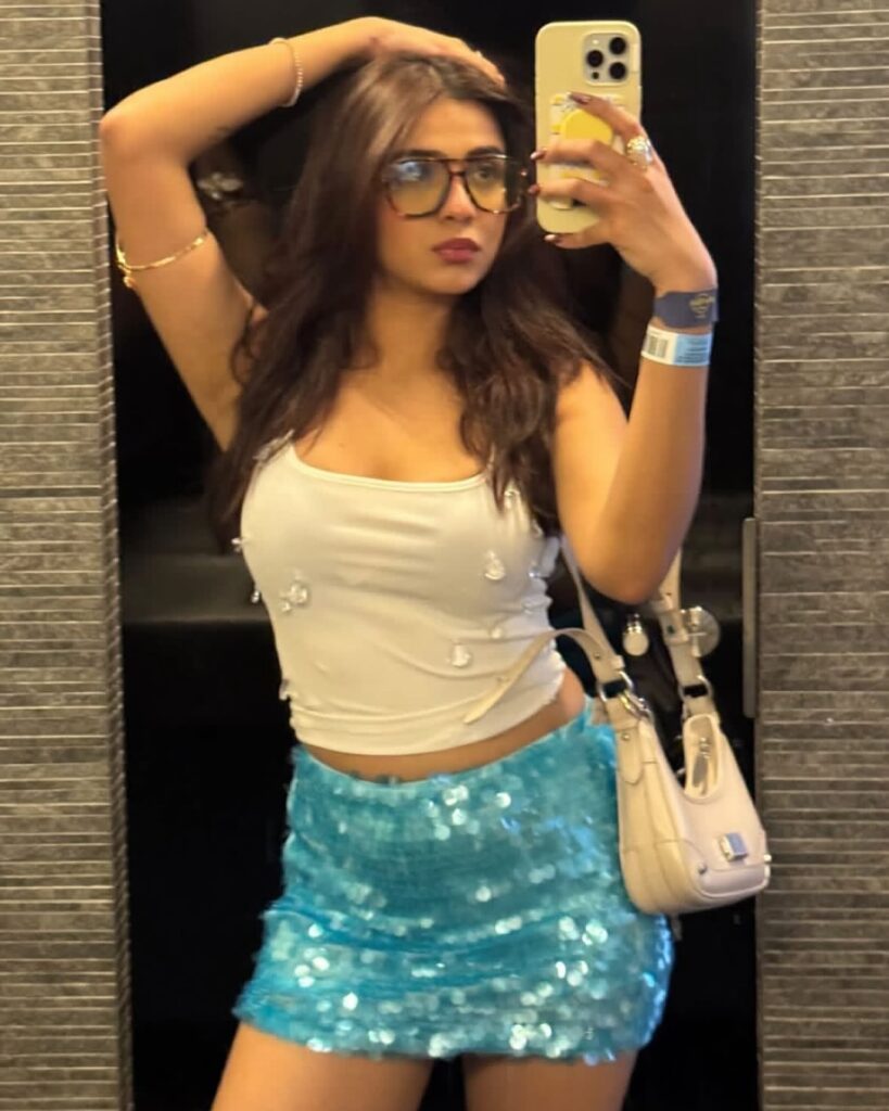 Mulher de pele clara, com blusa branca e saia de paetê azul 