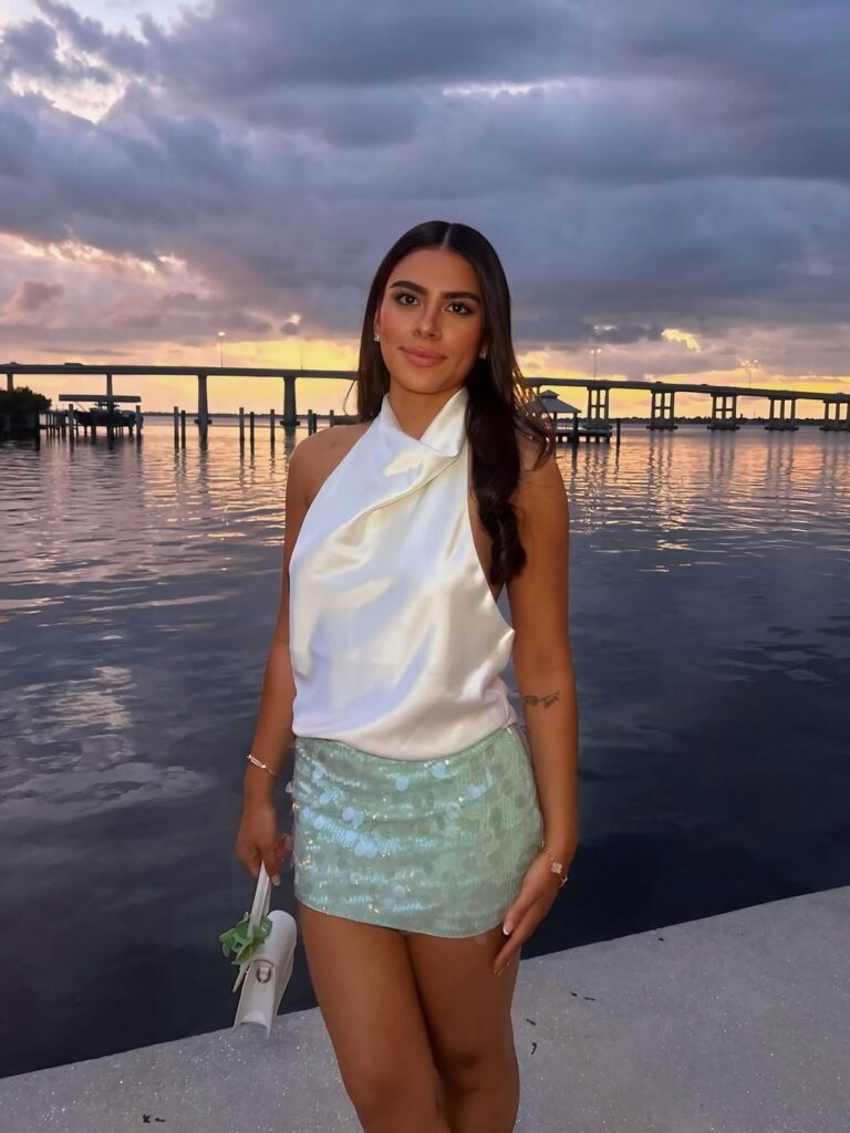 Mulher de pele clara, com blusa branca e saia de paetê azul 