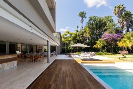 Paisagismo ao redor da piscina com cadeiras e ombrelone