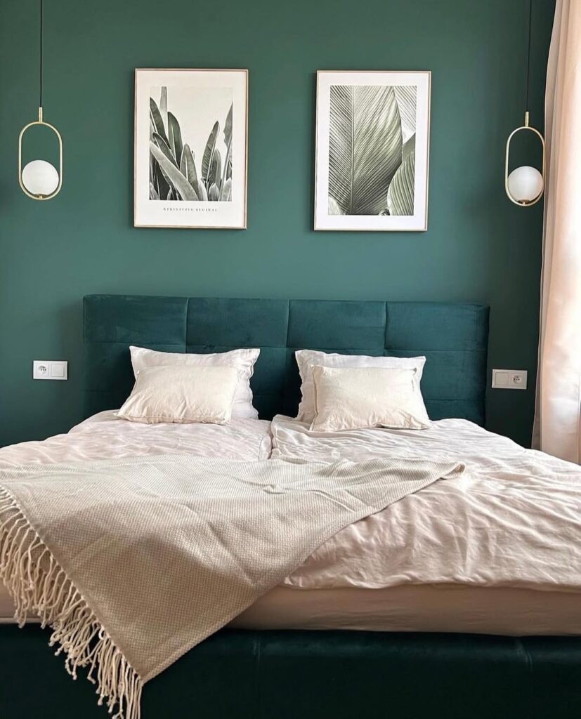 Quarto com parede e cama verde em tons diferentes, quadros com fundo branco na parede e arandelas