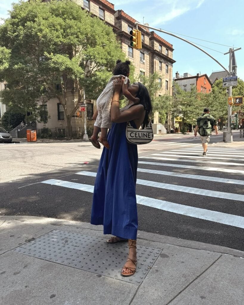 Mulher negra e magra com look de vestido azul, bolsa e rasteirinha boho