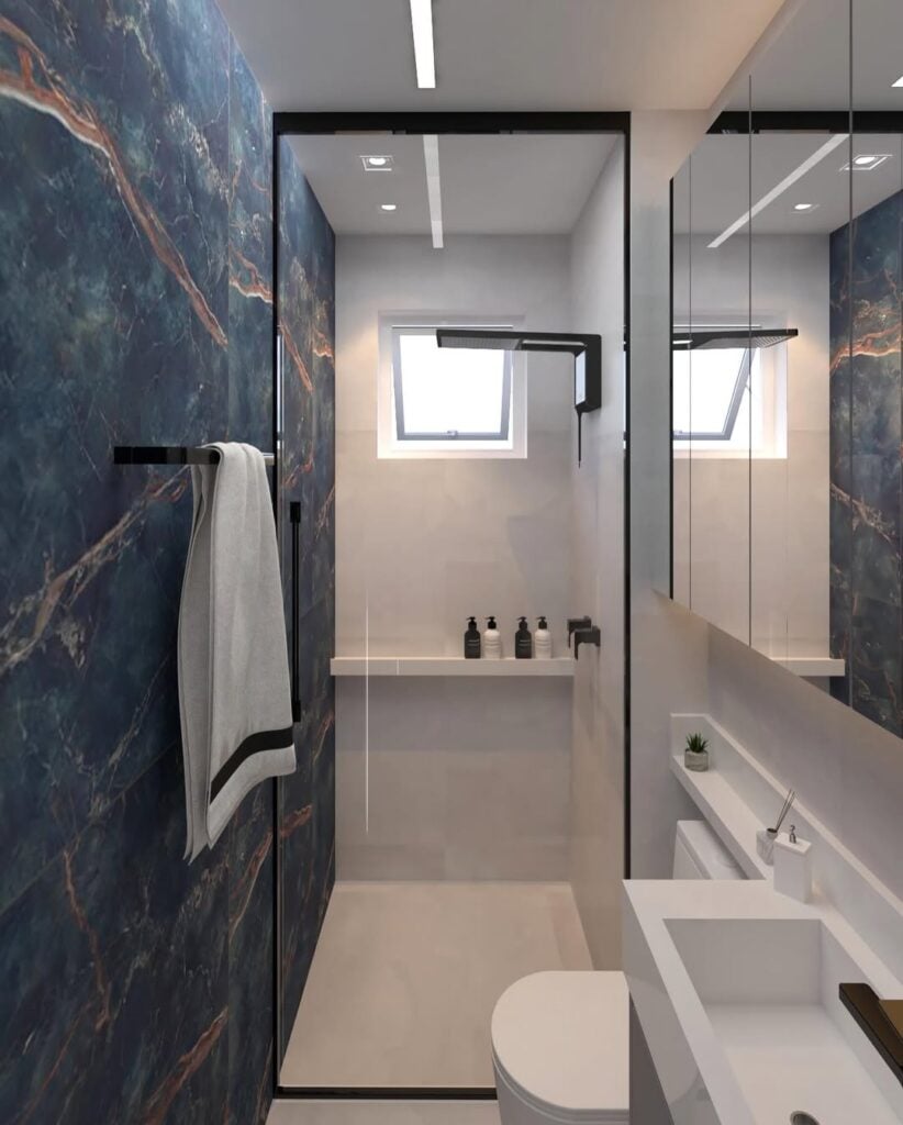 Banheiro com parede revestida de porcelanato azul, louças e parede branca, e detalhes em metal preto