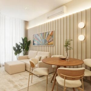 Sala de jantar com mesa redonda de madeira, cadeiras estofadas em bege e sofá claro