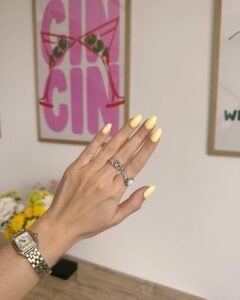Mão de pele clara, com anéis em prata e unha amarelo-manteiga