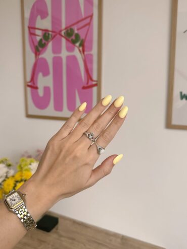 Mão de pele clara, com anéis em prata e unha amarelo-manteiga