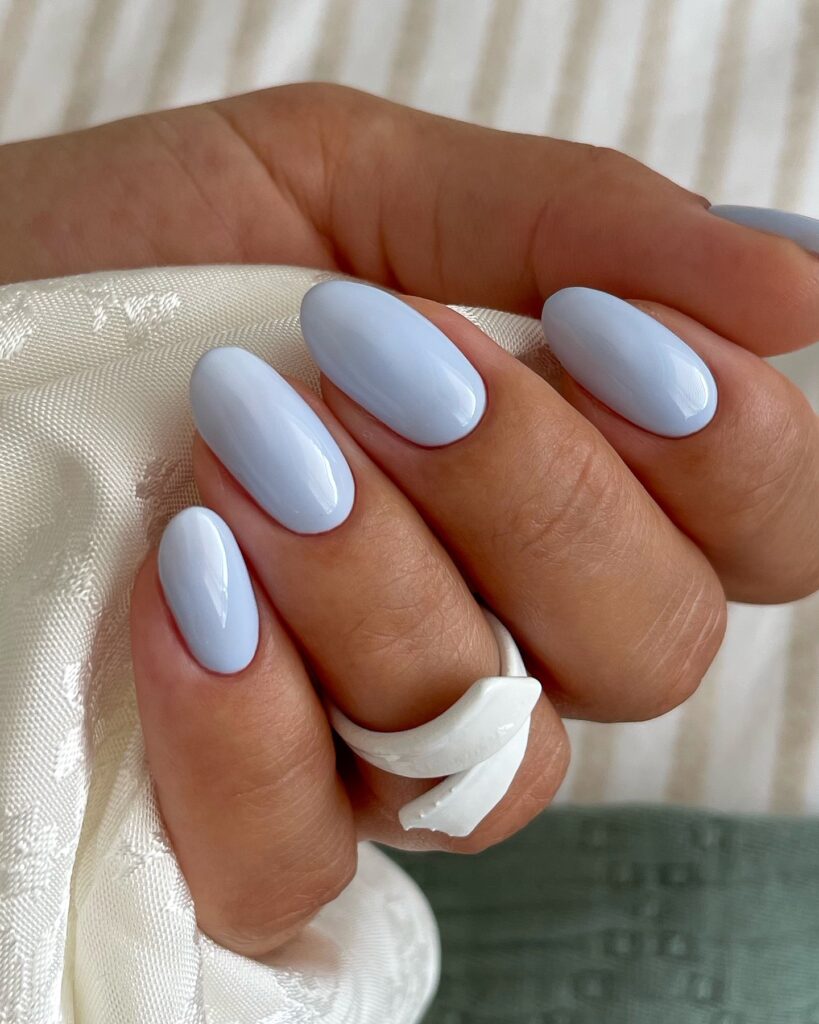 Unha com esmalte azul glacial em mão de pele branca