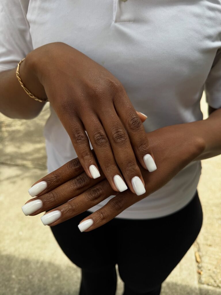 Unha com esmalte branco Cloud Dancer em mão de pele preta