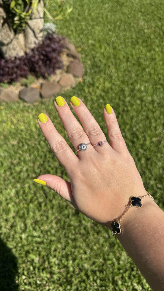 Mão de pele clara, com acessórios em prata e dourado e unha arredondada verde pistache