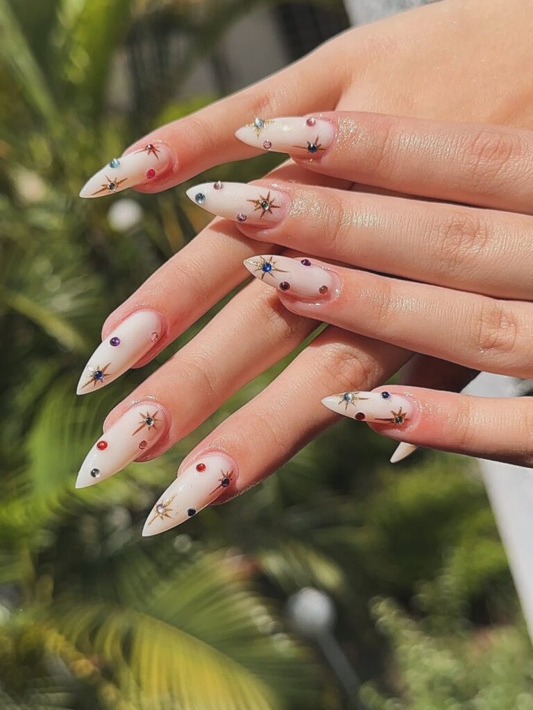 Mãos de pele clara, com unha stiletto com strass