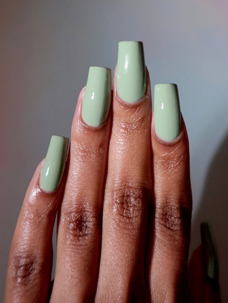 Unha verde e delicada em mão de pele negra