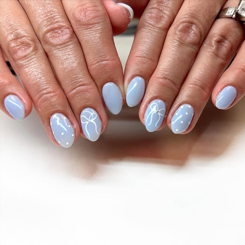 Unha azul e delicada com nail art branca em mão de pele branca