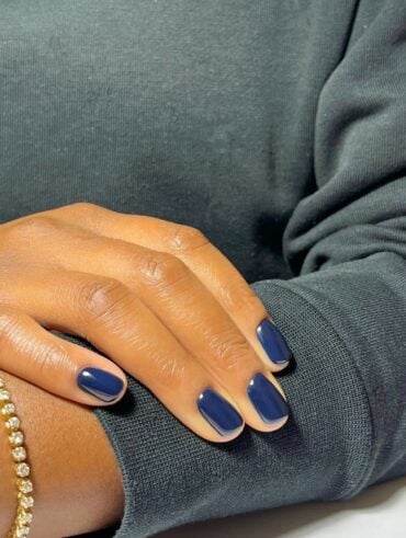 Unhas chiques e elegantes em mão de pele negra com esmalte azul petróleo
