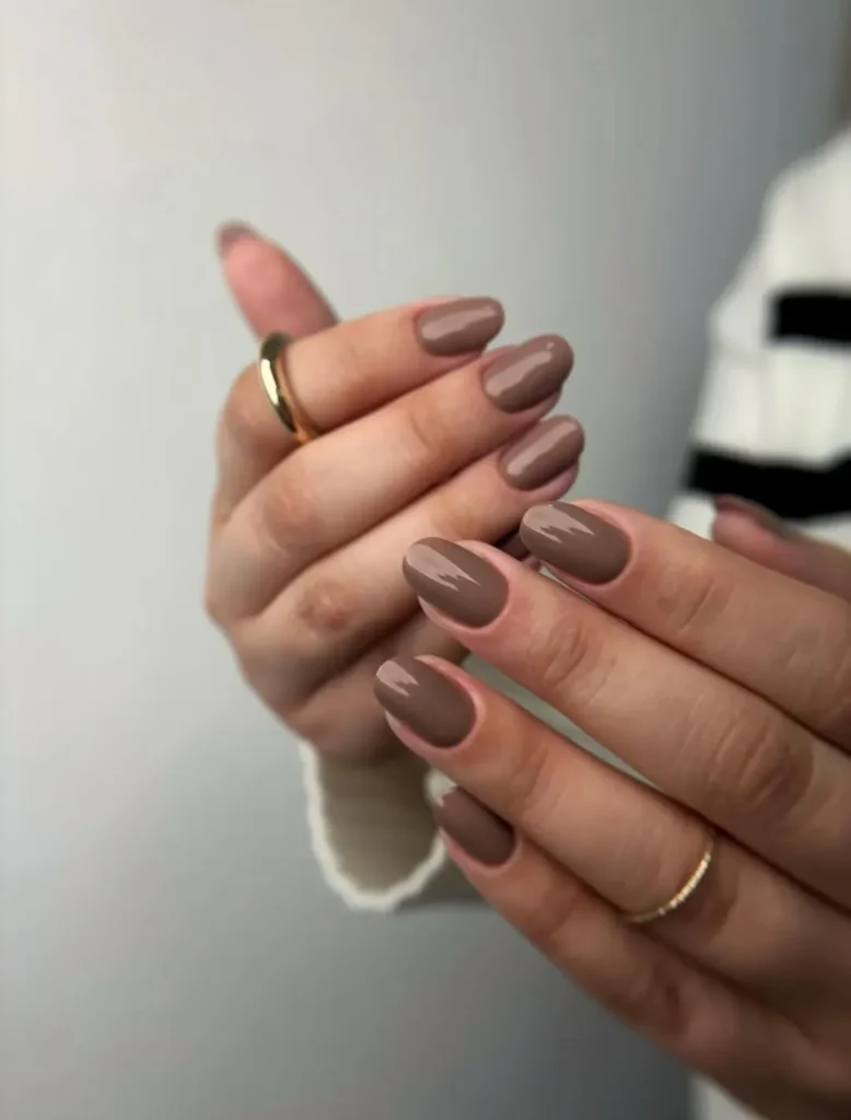 Mãos de pele clara, com anéis em dourado e unha amendoada Mocha Mousse