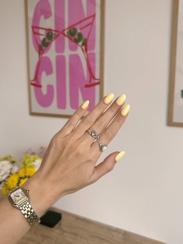 Mão de pele clara, com anéis em prata e unha amarelo-manteiga