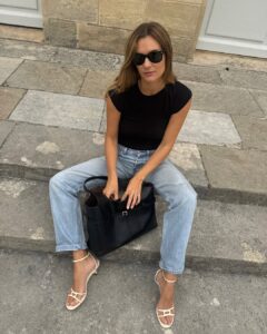 Mulher jovem usando blus preta, calça jeans e salto alto