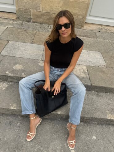 Mulher jovem usando blus preta, calça jeans e salto alto