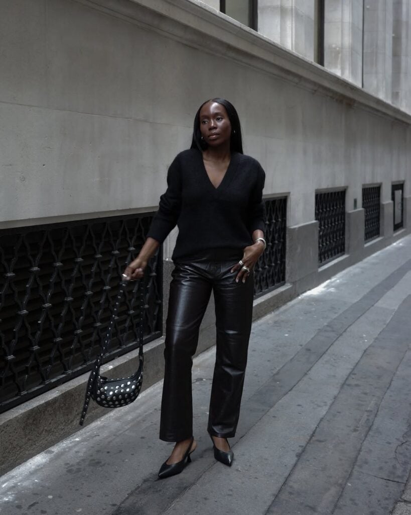 mulher jovem magra e de pele negra com suéter, calça de couro e sapato de salto alto bico fino