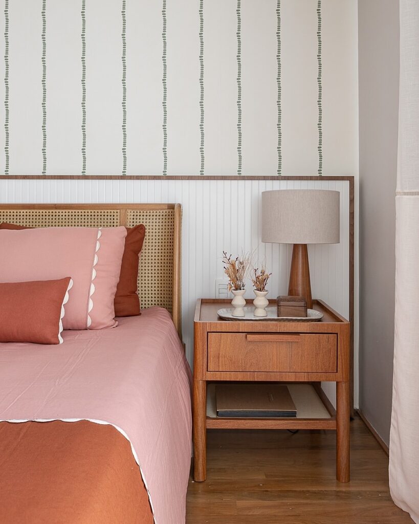 Cama com cabeceira de palhinha e mesa de cabeceira de madeira com gaveta, bandeja com enfeites
