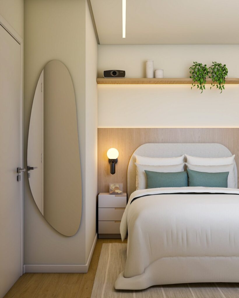 Quarto com espelho orgânico ao lado da porta, prateleira de madeira acima da cabeceira, arandela e mesa de cabeceira com gavetas