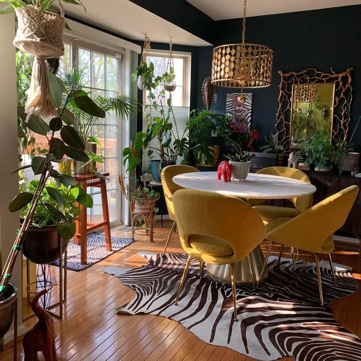 Ambiente com mesa redonda branca, poltronas amarelas, plantas e tapete de zebra