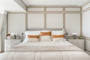 Quarto com parede branca, boiseries em tom mais escuro e cabeceira estofada cinza