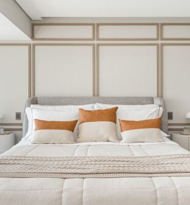 Quarto com parede branca, boiseries em tom mais escuro e cabeceira estofada cinza