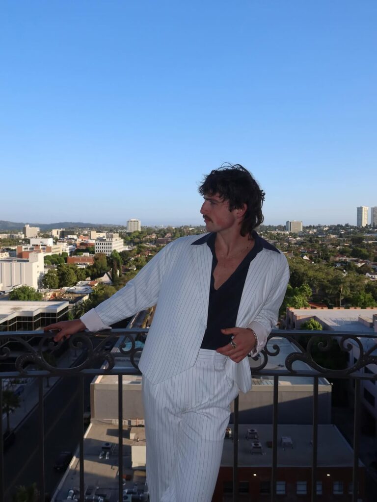 Benson Boone, com look preto e branco e corte de cabelo mullet