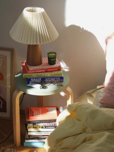 Decoração com livros e abajur na mesa de cabeceira