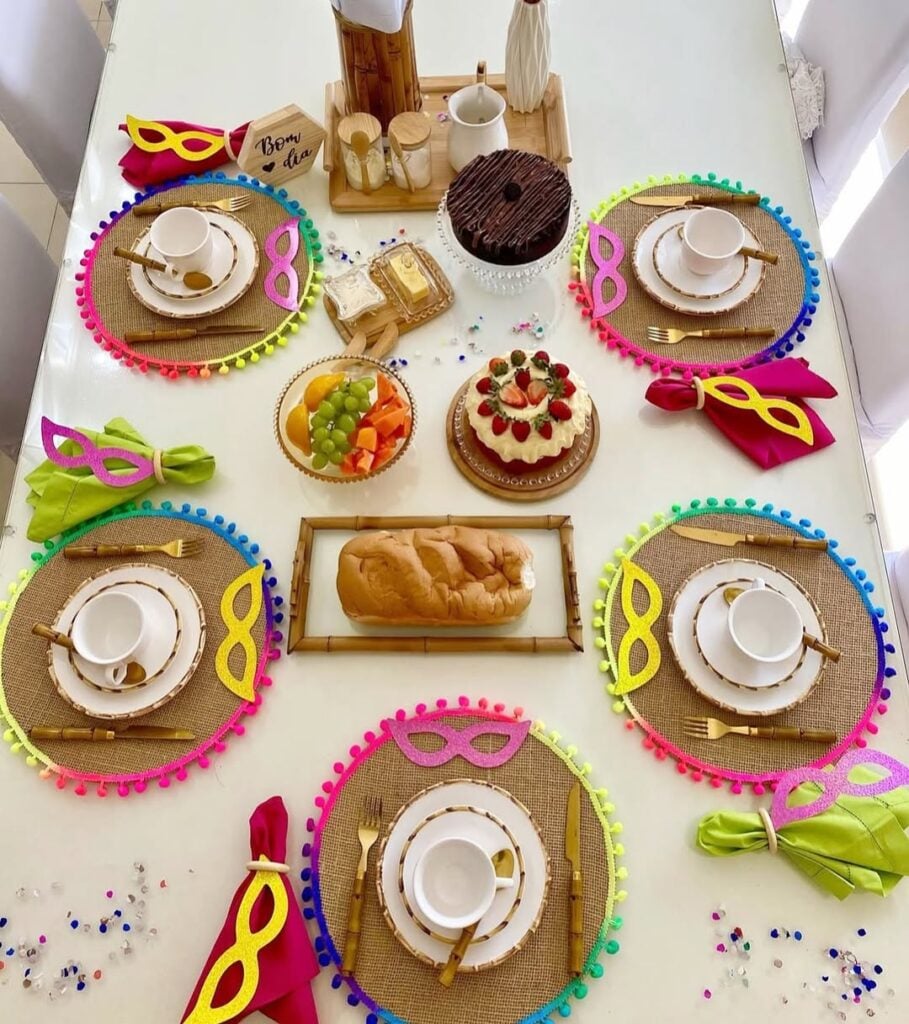 Mesa posta de café da manhã carnavalesco com sousplats com bordas coloridas e máscaras