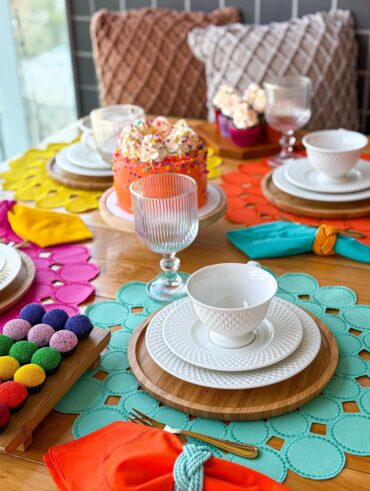Mesa posta de café carnavalesco com sousplats e docinhos coloridos
