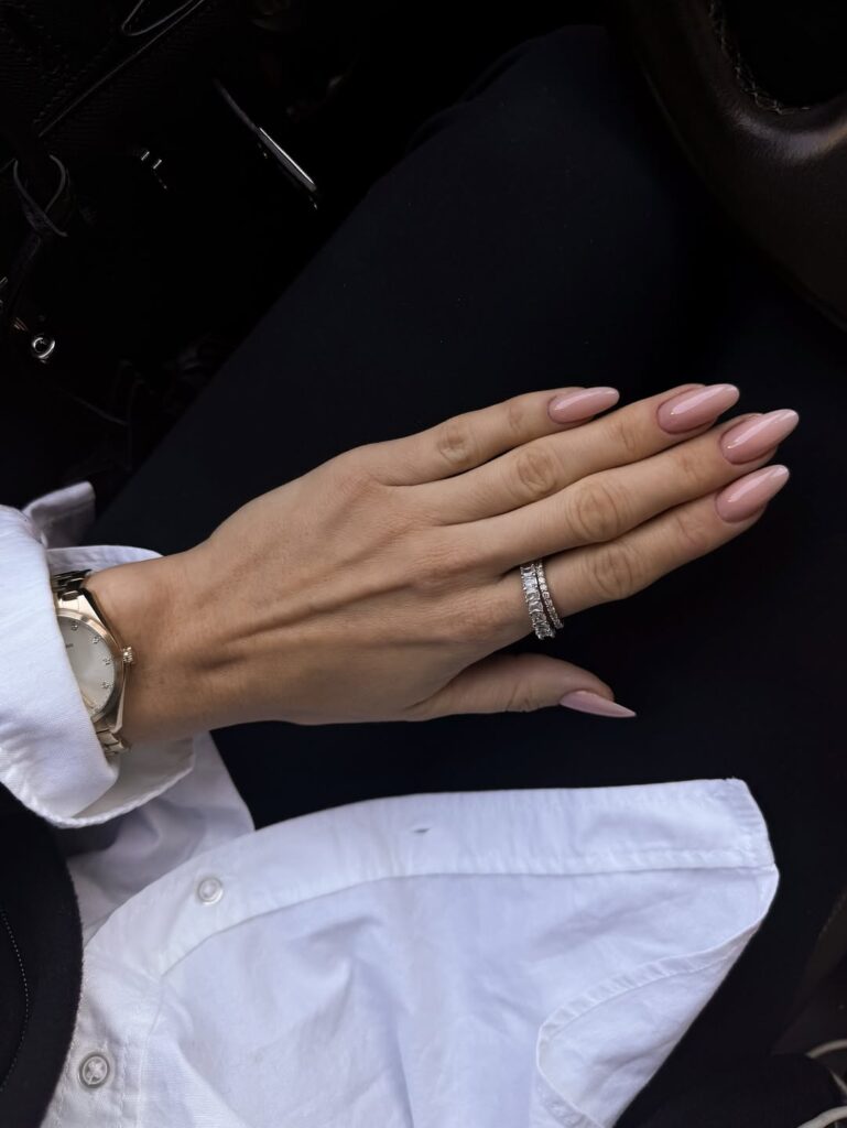 Mão de pele clara, com anéis em prata e unha amendoada nude-rosado