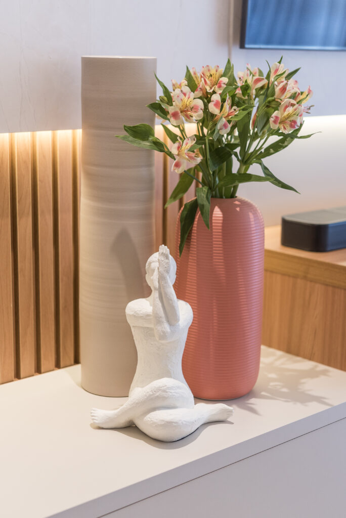 Vaso rosa com flores e escultura branca de mulher em posição de ioga