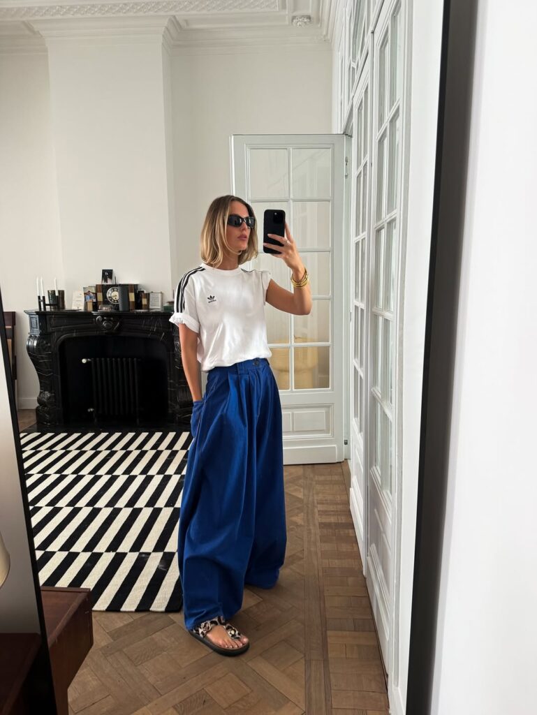 Mulher de pele clara, com blusa branca, calça azul e papete animal print