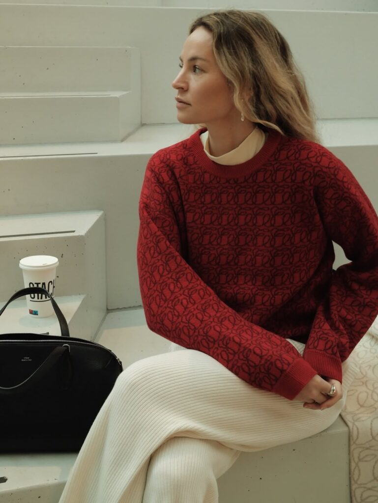 Mulher de pele clara, com suéter vermelho e calça branca